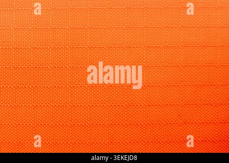 Bright vibrant orange texture on fabric surface featuring subtle grid pattern creating an energetic warm abstract background for creative graphic desi Stock Photo
