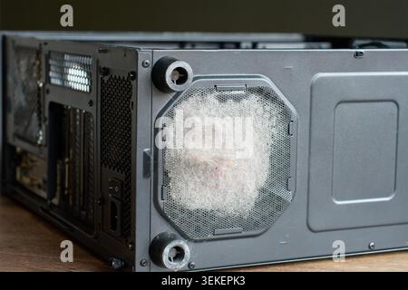 Close-up of heavy dust buildup on computer case ventilation mesh and fan filter. Concept of PC maintenance, airflow problem, cleaning, and hardware service Stock Photo