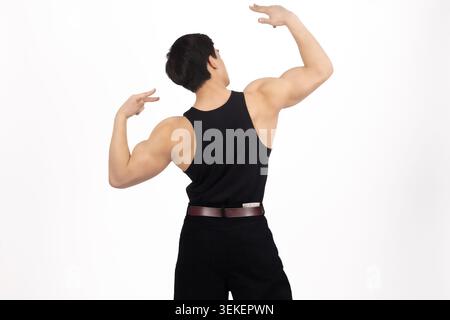 Muscular man back view flexing shoulder muscles looking over shoulder Stock Photo