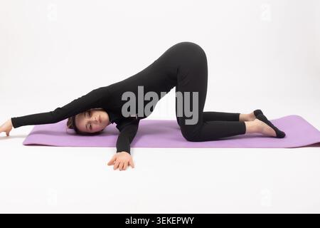 Young woman practicing yoga stretching exercise pose on fitness mat Stock Photo