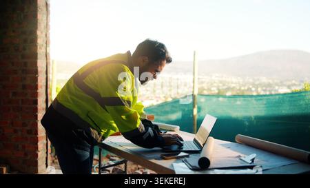 Architect, man or typing on laptop at construction site for digital design, report draft or planning. Architecture, person and tech on blueprint Stock Photo