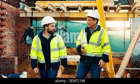 Walk, architect and men in construction for site inspection, project planning and building safety. Team, people and tablet with blueprint outdoor for Stock Photo