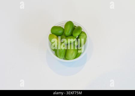 Bright green edamame beans in a small plastic pot on a white background for poke bowl toppings. Stock Photo