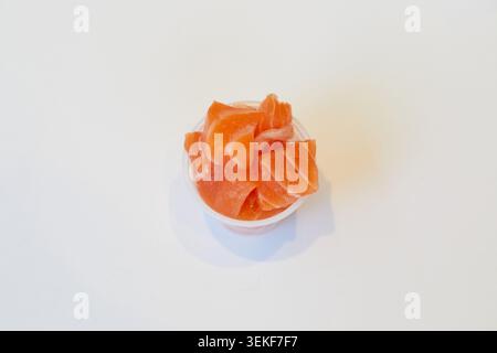 Fresh salmon pieces in a small plastic pot on a white background for poke bowls, sushi bowls and seafood rice bowls. Stock Photo