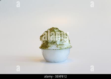 Matcha green tea shaved ice dessert in a clear plastic bowl on a white background. Stock Photo