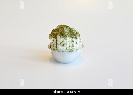 Matcha green tea shaved ice dessert in a clear plastic bowl on a white background. Stock Photo