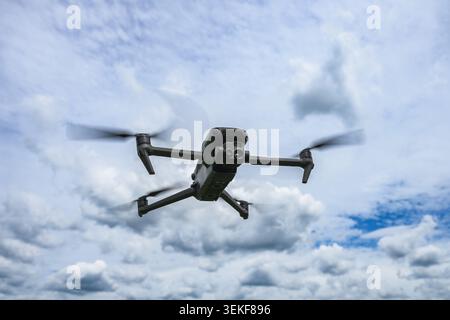 Modern quadcopter drone hovering in the air against dramatic cloudy sky. Unmanned aerial vehicle with camera used for photography, inspection, mapping Stock Photo