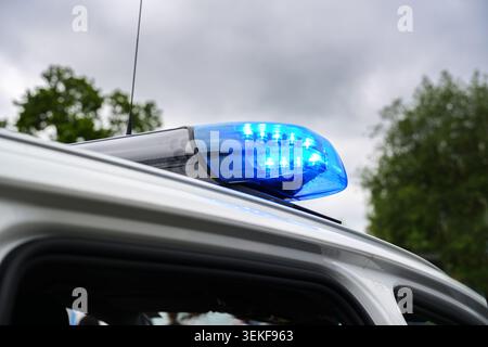 Flashing blue light on a police car during an operation against a cloudy sky, concept for rescue, emergency and crime fighting, selected focus, narrow Stock Photo