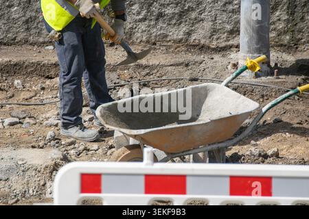 Unrecognizable builder working with shovel on dusty site The Concept of urban development Stock Photo