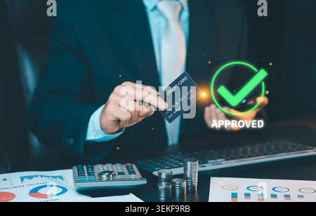Businessman holding credit card with green approved check mark icon on virtual screen. Successful online payment transaction concept. Stock Photo