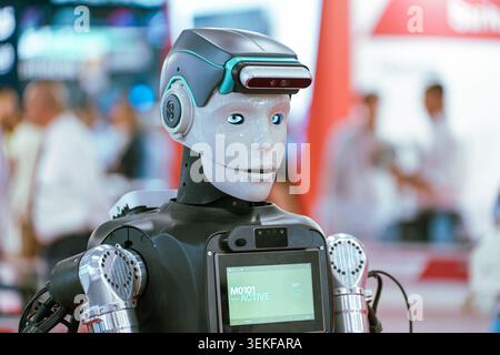 A close-up profile view of an advanced humanoid service robot with illuminated blue eyes and a head-mounted sensor array on display at an automation t Stock Photo