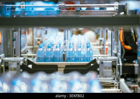 Packs of plastic water bottles move along an automated conveyor belt system during a packaging demonstration at an industrial manufacturing trade fair Stock Photo
