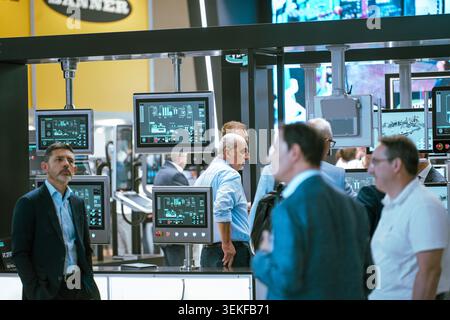 Multiple industrial control terminal screens display active monitoring software and process logistics diagrams during an automation technology trade s Stock Photo