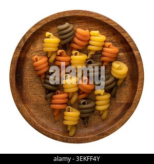 Tricolor cavatappi pasta arranged on a wooden plate viewed from above on white background. Stock Photo