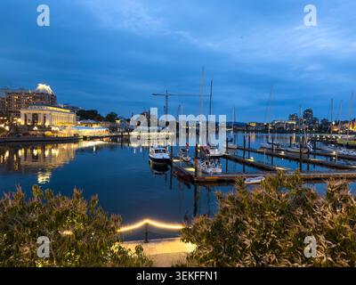 Evening view of Victoria Inner Harbour with marina docks, sailboats and reflections on calm water under a blue twilight sky in Victoria,BC,Canada. Stock Photo