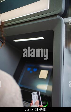 Woman inserting credit card into ATM for banking transaction Stock Photo