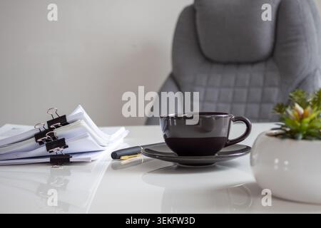 Dark ceramic cup sits on a sleek white desk Stock Photo