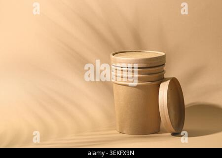 Craft paper soup cup with shadow on brown paper background. Empty container for take away food. Ecological individual package. Zero Waste. Stock Photo