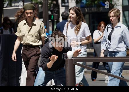 Young man records himself with a smartphone on a Paris street as pedestrians pass by. Stock Photo