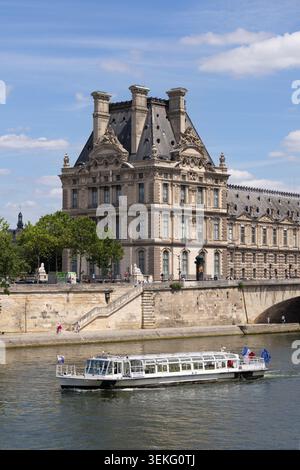 Sightseeing boat passes the Louvre Palace on the River Seine in Paris. Stock Photo