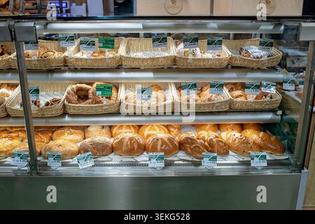Batumi, Georgia - May 30, 2026: Various fresh buns, croissants, and loaves of bread in wicker baskets on shelves of an Agrohub supermarket display Stock Photo