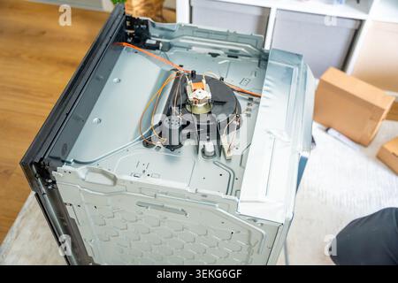 Built in electric oven with removed top panel during repair process at home. Household appliance maintenance and professional repair service concept Stock Photo