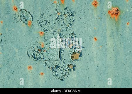 Abstract shape of cracking and peeling light blue paint on an old steel surface with scattered rust dots. High-detail texture for grunge designs. Stock Photo