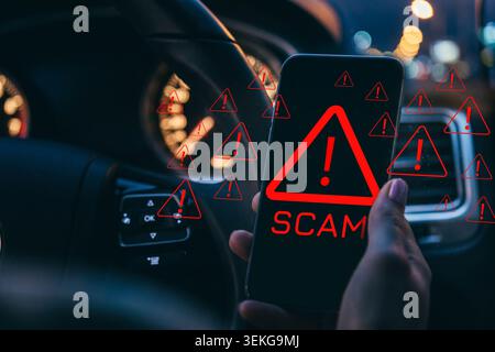 Scam message appears on a phone while someone drives at night Stock Photo