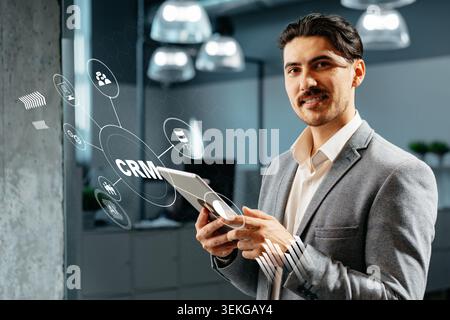 Man uses tablet to manage customer relationships in modern office space Stock Photo
