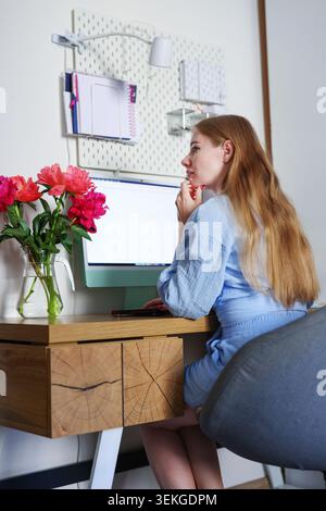 Beautiful blonde woman using mobile phone at stylish workspace, casual indoor lifestyle scene with natural light and feminine atmosphere. Stock Photo