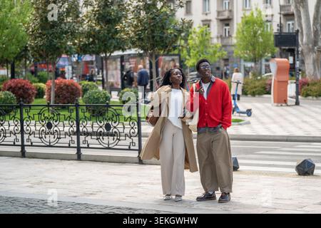 Smiling positive african american man and woman friends enjoying modern city area on daily walk Stock Photo