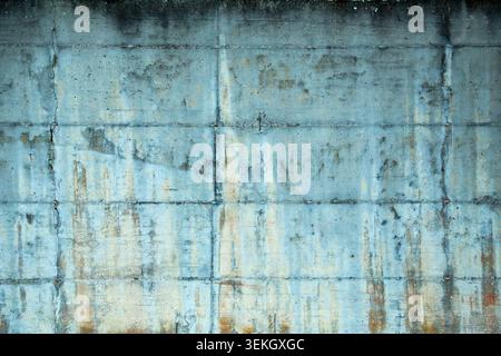 This professional close up outdoor photograph captures the detailed and weathered texture of a solid concrete wall. The camera focuses straight on the industrial surface revealing deep cracks Stock Photo