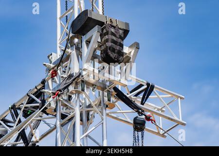 Professional stage light truss tower setup with mechanical hoist chains and safety sandbag gear, outdoor concert event construction industry concept Stock Photo