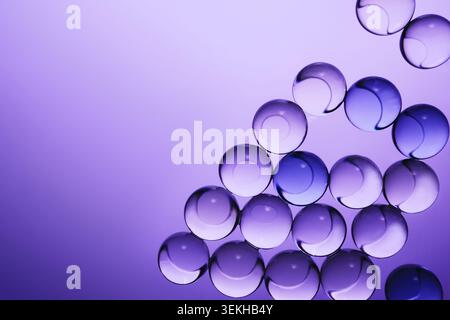 Translucent spheres creating an abstract pattern with light refractions on vibrant purple background Stock Photo