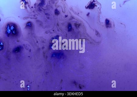 Violet Blue Liquid Mottled Particulates Macro Studio Background Closeup In Shallow Translucent Container Under Cool Low Light Showing Diffused Streaks And Clustered Dark Granules. Stock Photo