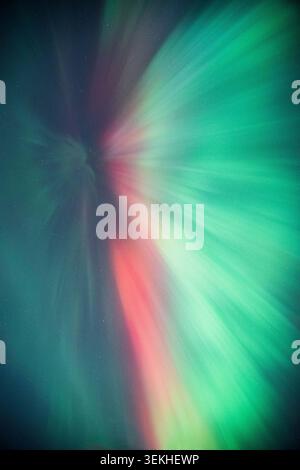 A mesmerizing aurora borealis corona fills the night sky with sweeping ribbons of emerald green and vivid red Stock Photo
