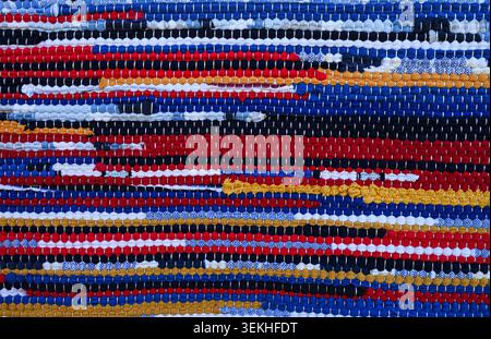 Colorful woven rug texture with bright striped pattern and handmade textile detail. Rustic fabric background for boho interiors. Stock Photo