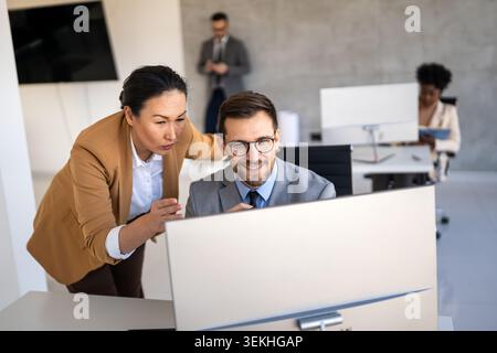 Happy multiethnic businesspeople laughing while collaborating on a new project in an office. Stock Photo