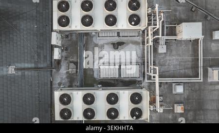 Top-down drone perspective showcasing large air conditioning units, ventilation systems, and piping on a weathered urban rooftop Stock Photo