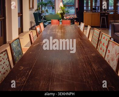 Long Rustic Wooden Conference Table with Colorful Vintage Chairs in a Cozy Lounge Space Stock Photo