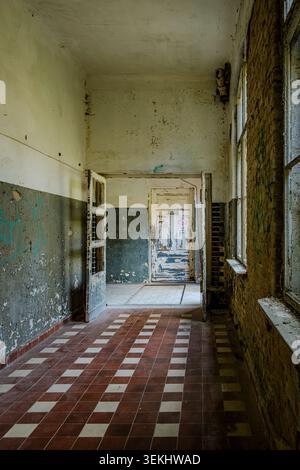 Long and dilapidated corridor in the former pulmonary sanatorium and abandoned site of Grabowsee Sanatorium, Oranienburg, Brandenburg, Germany. Stock Photo