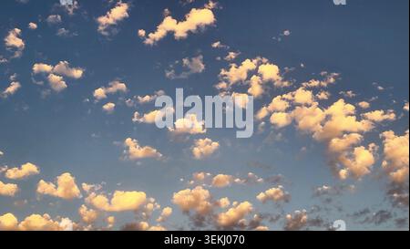 Golden Evening Cloudscape with Small Illuminated Clouds in a Deep Blue Swiss Sky Stock Photo