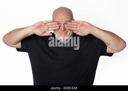 Smiling 60 Year Old Man Covering Eyes With Open Hands And Peeking Isolated On White Background. Stock Photo