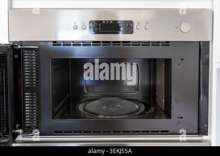 Close-up view of the inside of a contemporary stainless steel microwave oven, showcasing the turntable and control panel Stock Photo