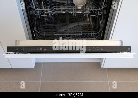 Close-up view of an open dishwasher interior and its sleek black control panel featuring buttons and indicator lights for different wash cycles Stock Photo