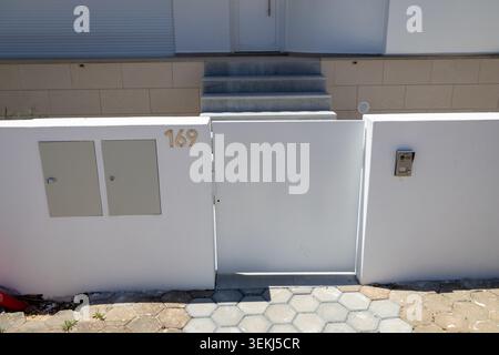 A contemporary entrance featuring a clean white gate, house number, and an integrated intercom system for secure access Stock Photo