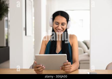 Young woman in wireless headphones using tablet at home Stock Photo