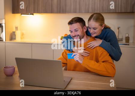 Middle-aged making purchases and reservations online using laptop and paying by card Stock Photo