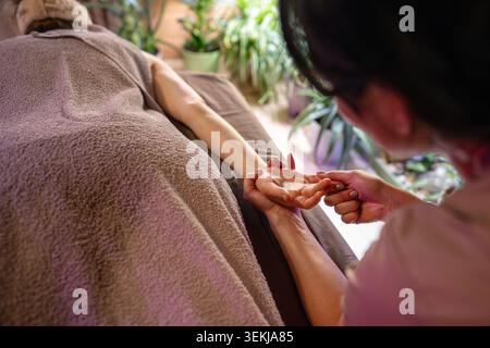 Cosmetologist in spa salon making relaxing gentle body massage for woman client lying on bed Stock Photo