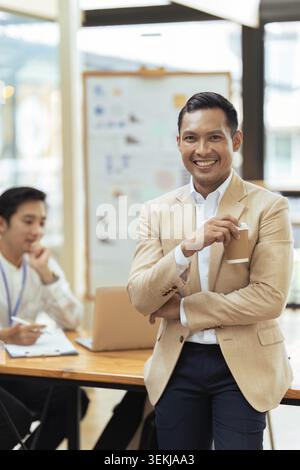 Portrait of happy and confident young man against background of his business team colleagues Stock Photo
